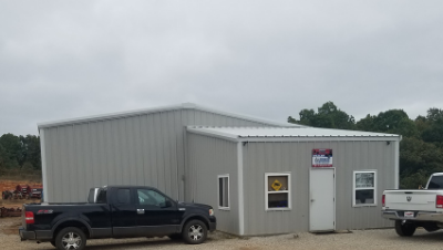 Gray metal office building with parked black pickup trucks on a cloudy day