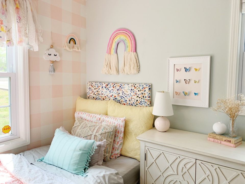 pink butterfly art beside pink check accent wall in little girls room