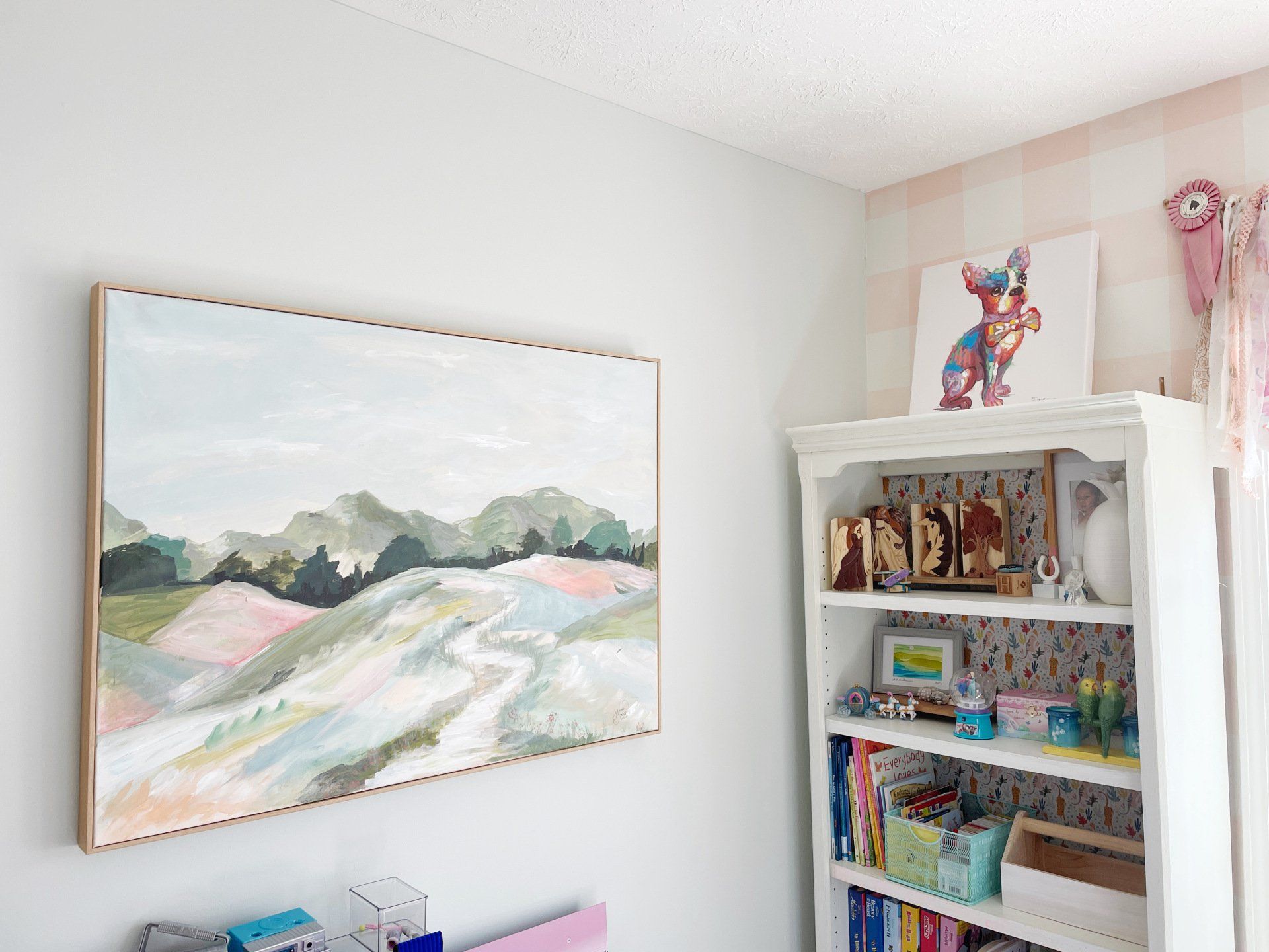 large framed canvas of pastel landscape in little girl's room beside bookshelf