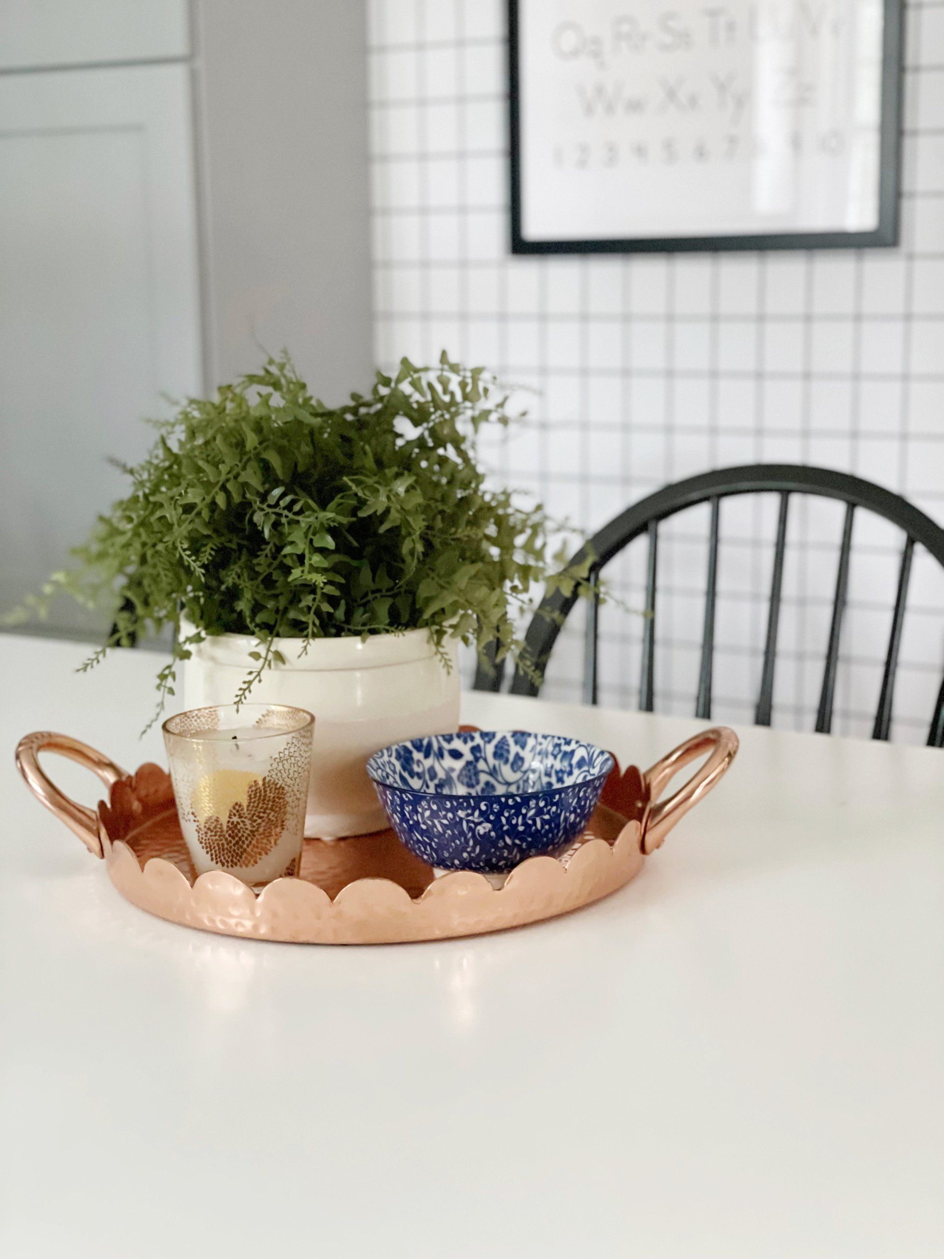 copper scalloped tray with faux plant with black and white checked wallpaper