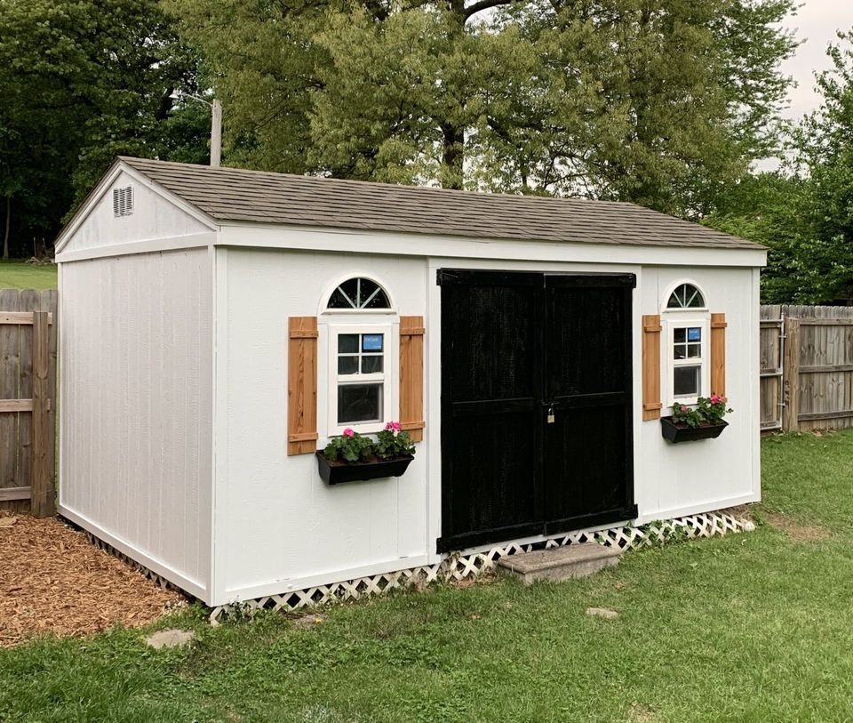 black and white shed with cedar shutters and window boxes
