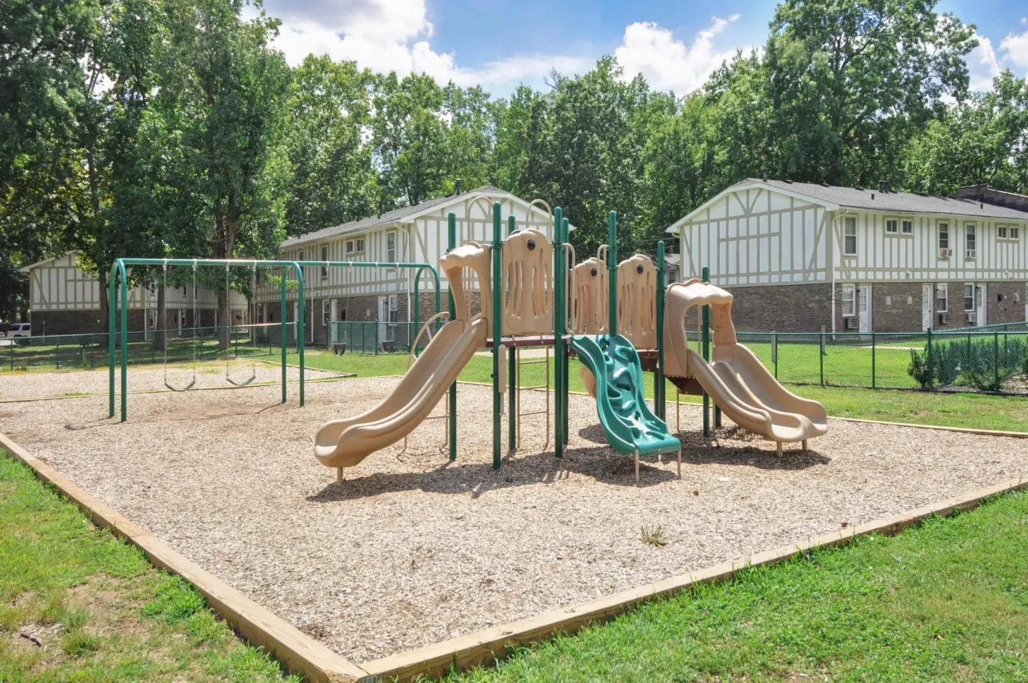 A playground with a slide and swings in a park.