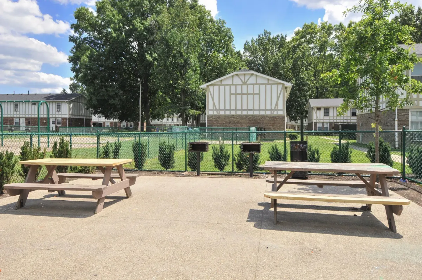 Two wooden picnic tables are in a gravel area