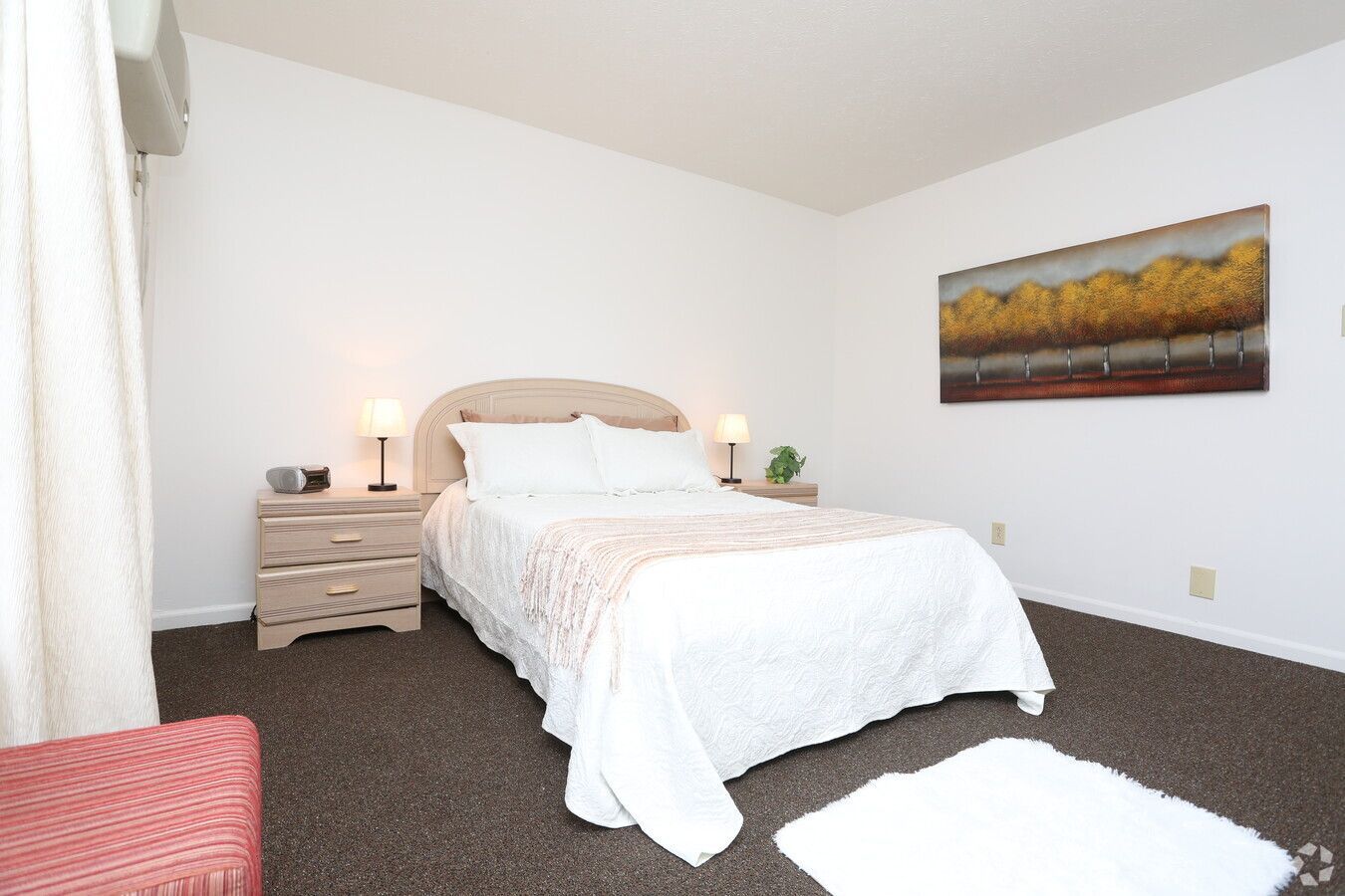 A bedroom with a large bed and a painting on the wall