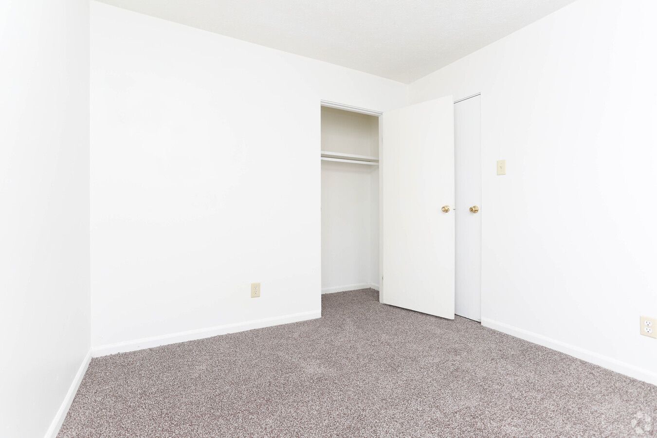 An empty bedroom with a closet and a carpeted floor.