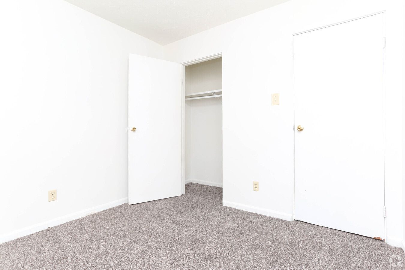 An empty bedroom with a closet and a carpeted floor.