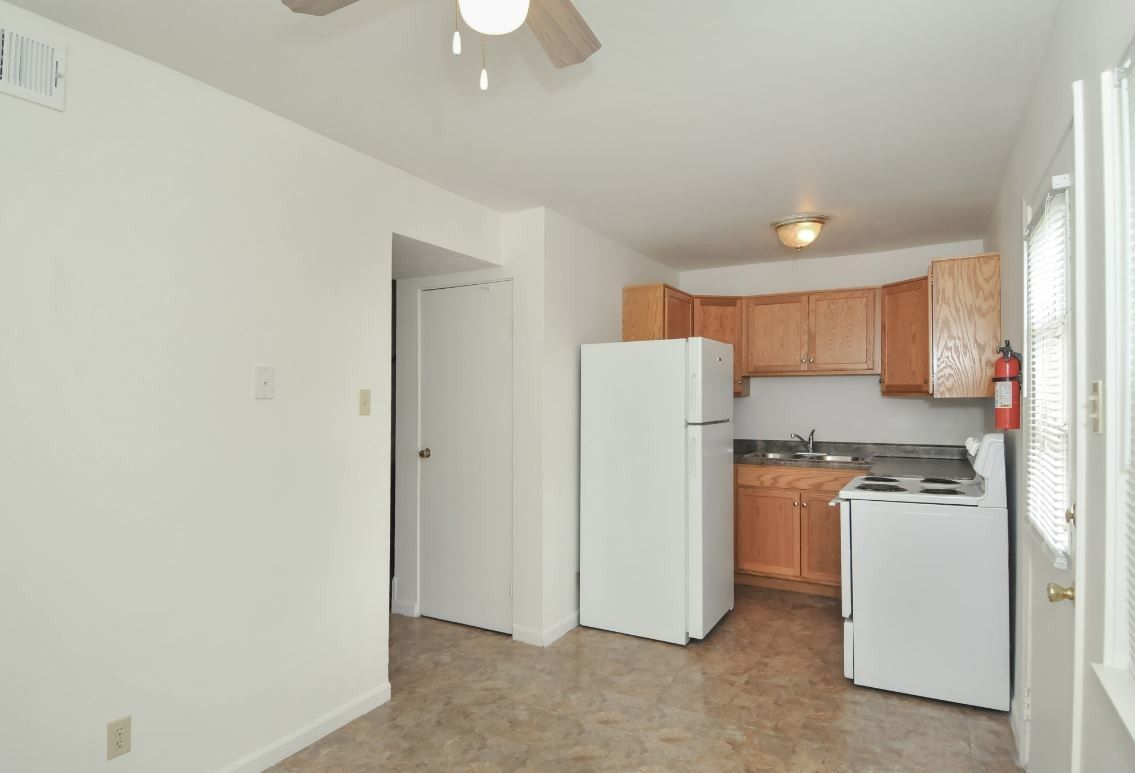 An empty kitchen with a white refrigerator and stove