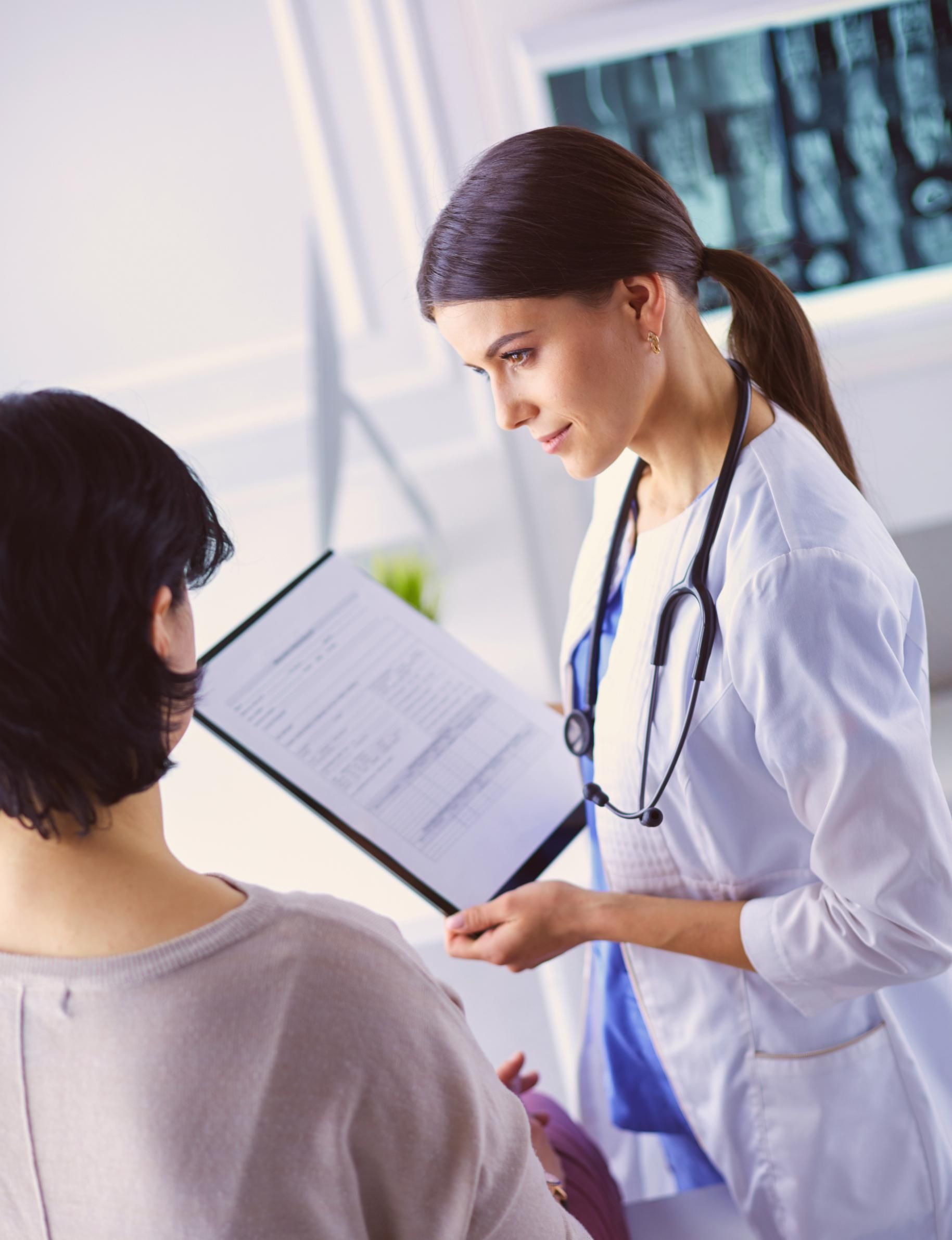 A doctor is talking to a patient while looking at an x-ray.
