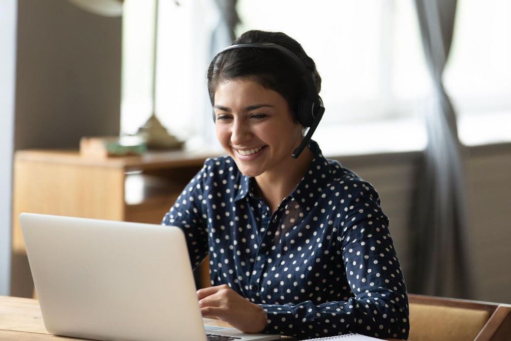 A woman wearing headphones is using a laptop computer.