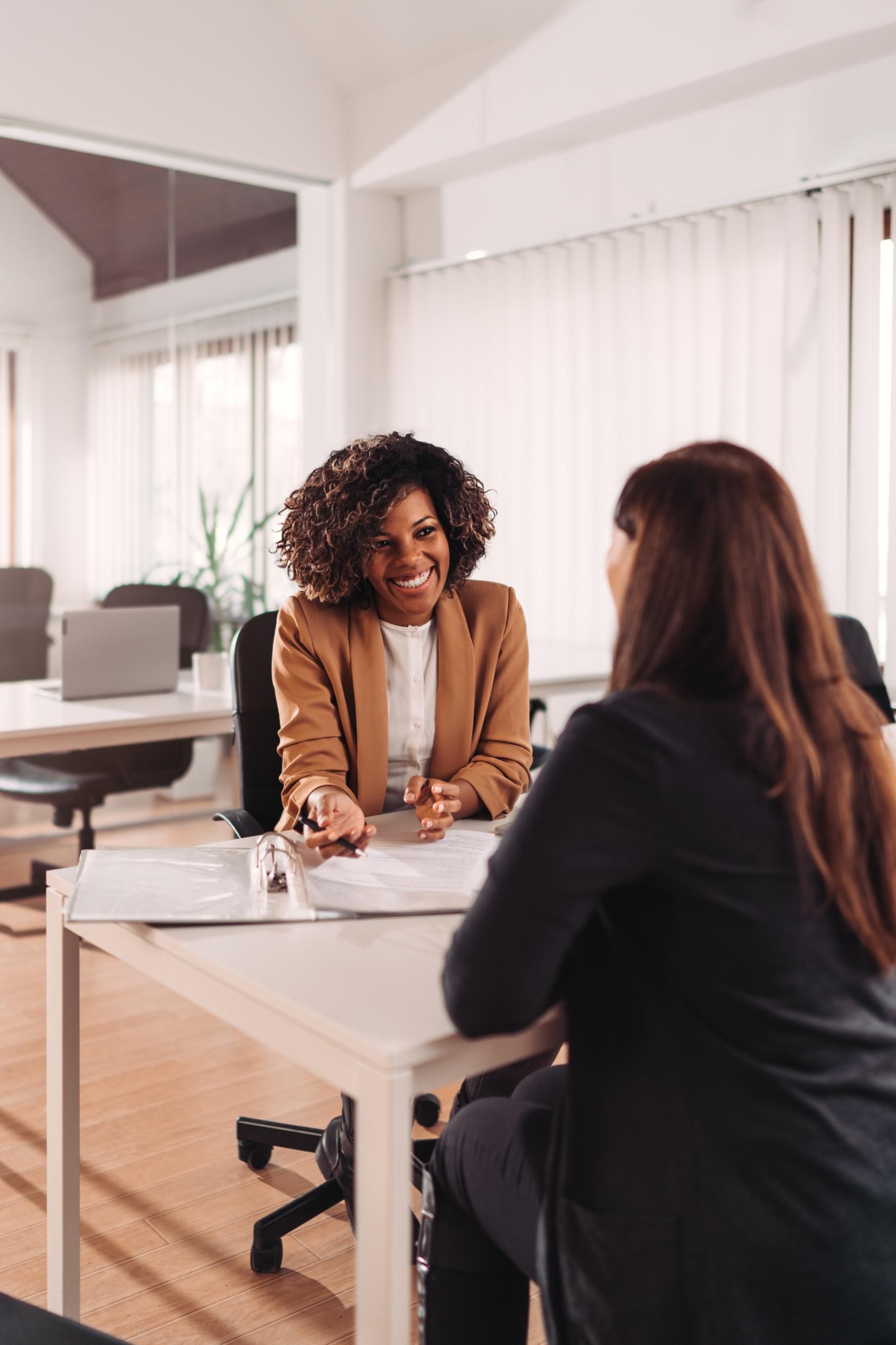 A woman is sitting at a table talking to another woman.
