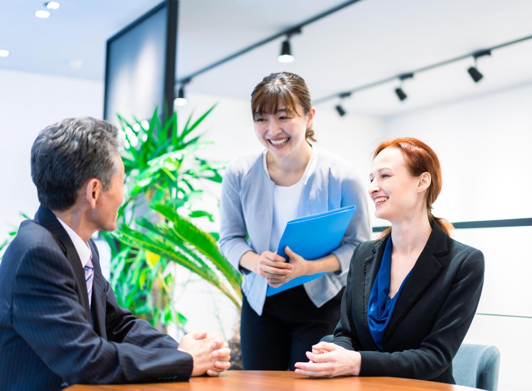 A group of people are sitting around a table having a meeting.