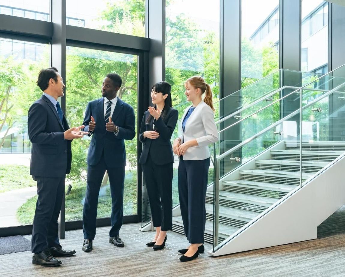 A group of business people are standing in a lobby talking to each other.