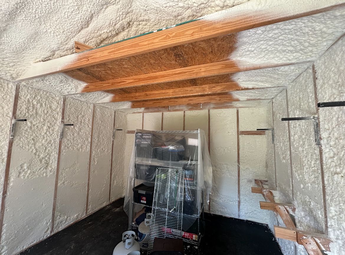 Interior of a room insulated with spray foam; unfinished wood beams and supports visible.