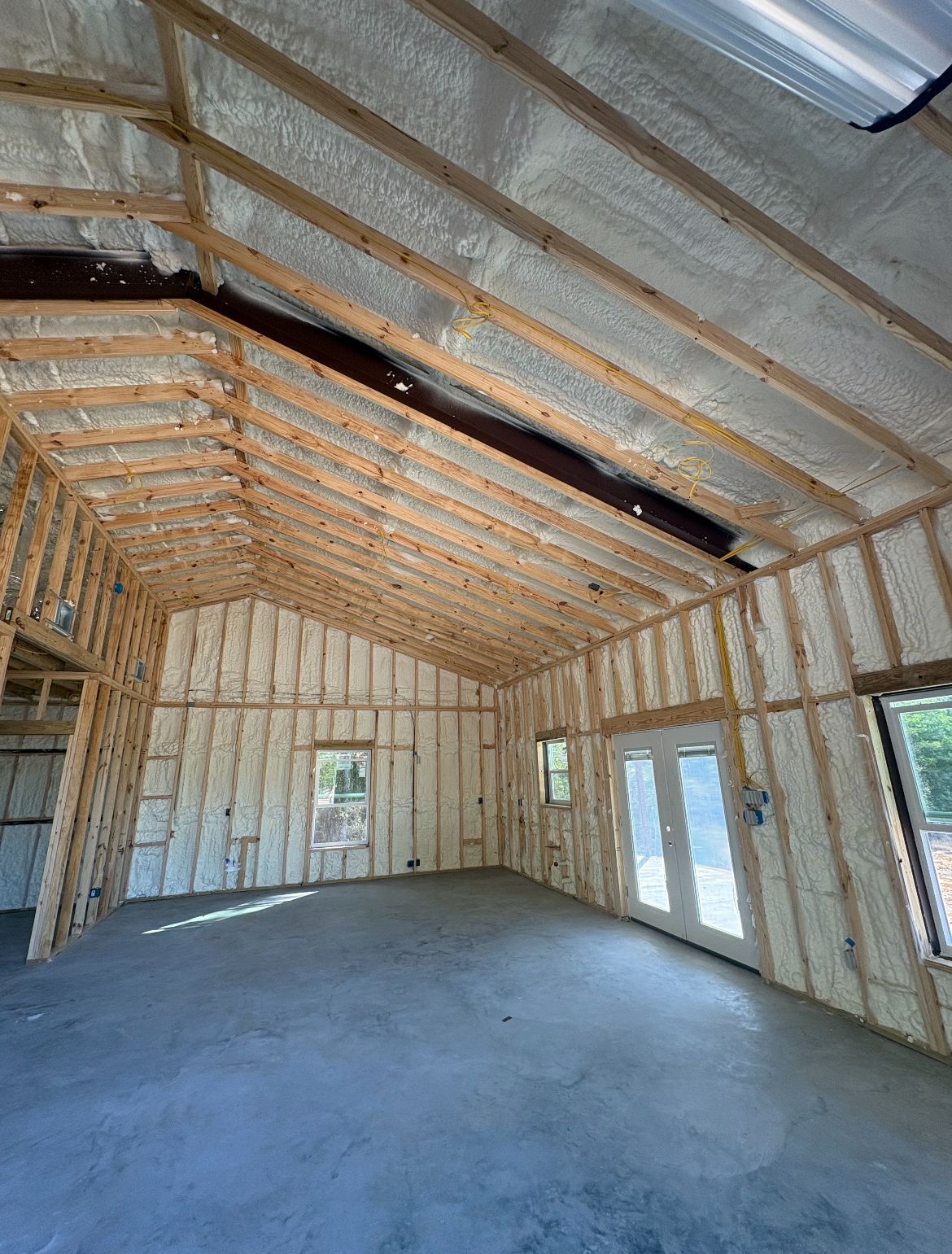 Interior of a building under construction, spray foam insulation on walls and ceiling, concrete floor.