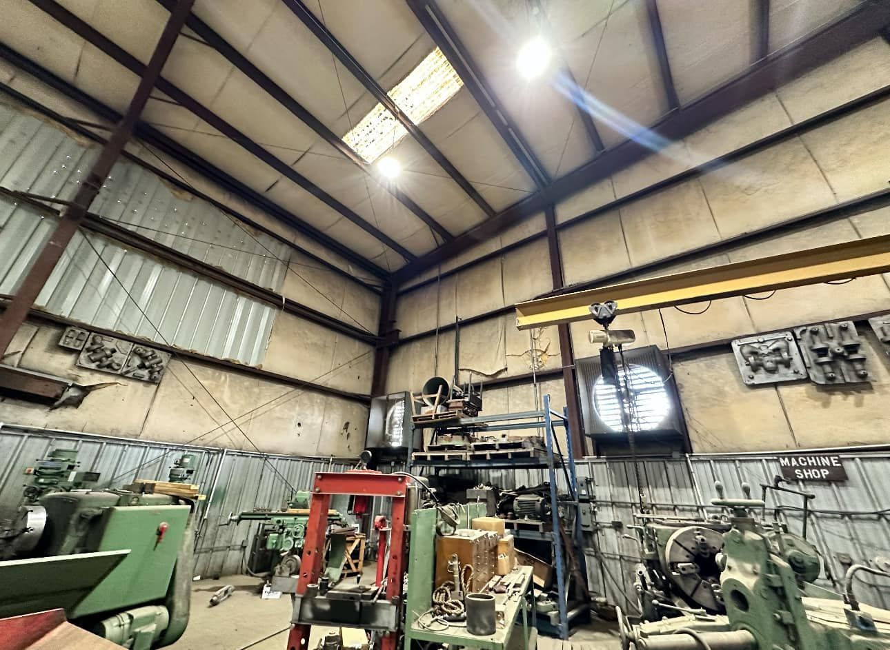 Workshop interior with machinery and equipment. Metal roof and walls. Bright overhead lights.