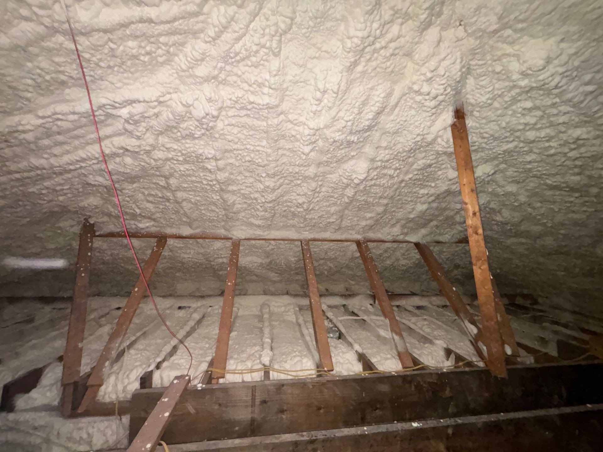 Attic with spray foam insulation on ceiling and rafters.