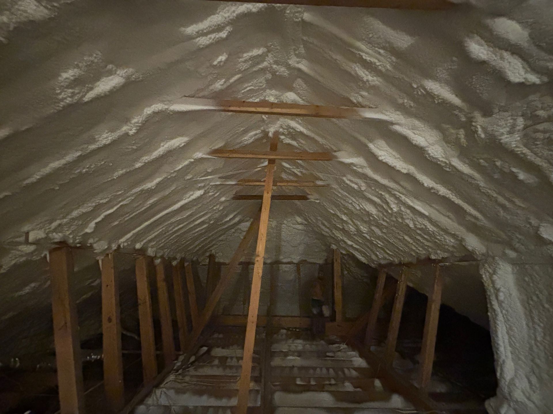 Attic interior with spray foam insulation between rafters and on the roof.