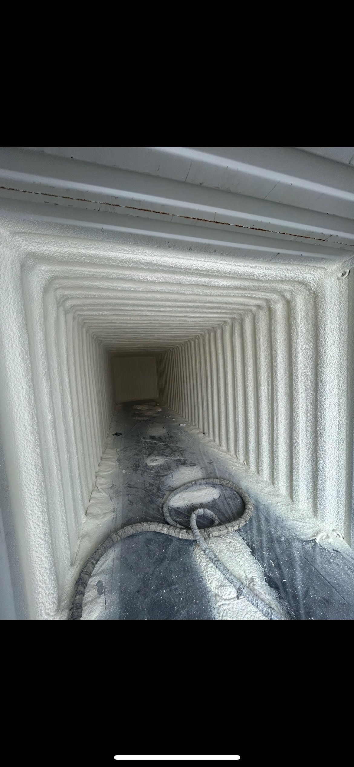 Inside view of a square duct or chimney covered in white residue.  A bucket is visible at the bottom.