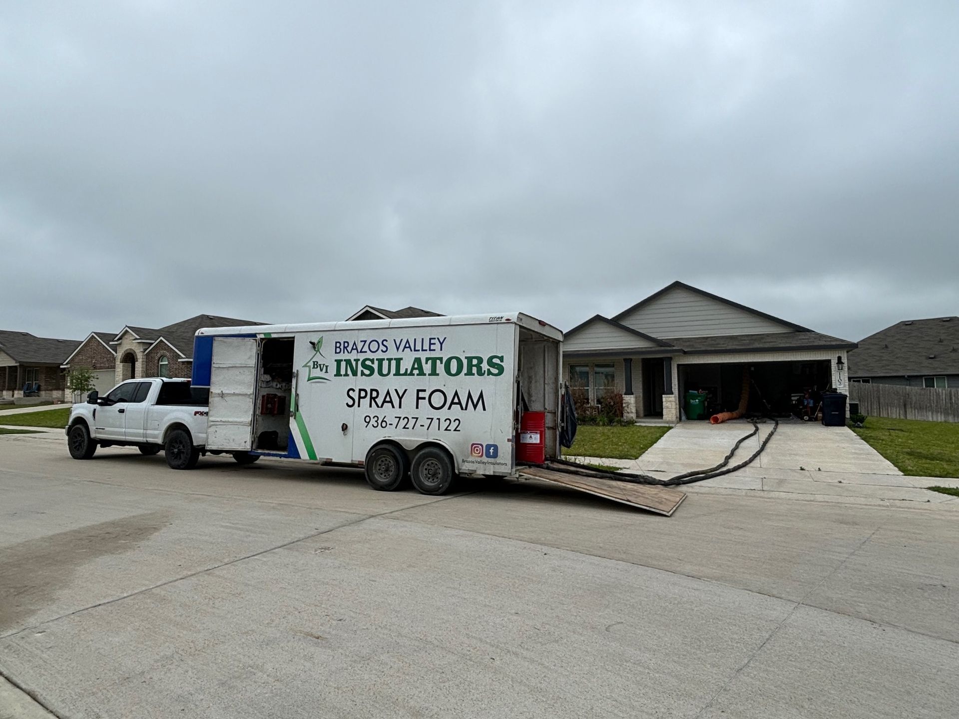 Spray foam insulation truck parked in front of a house on a cloudy day.