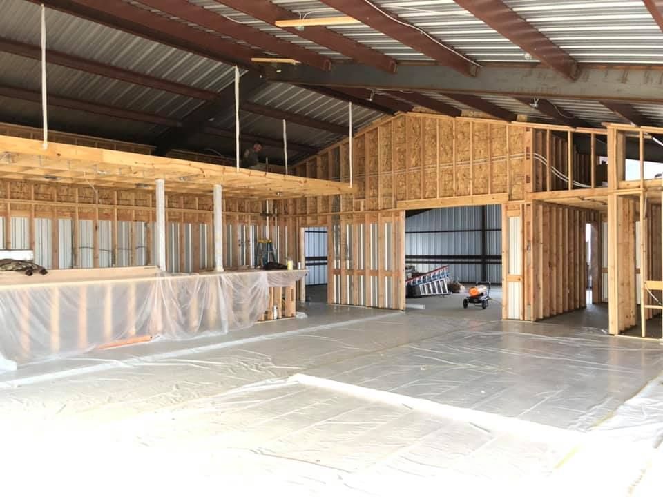 Interior of a building under construction, showing wooden framing and concrete floor.