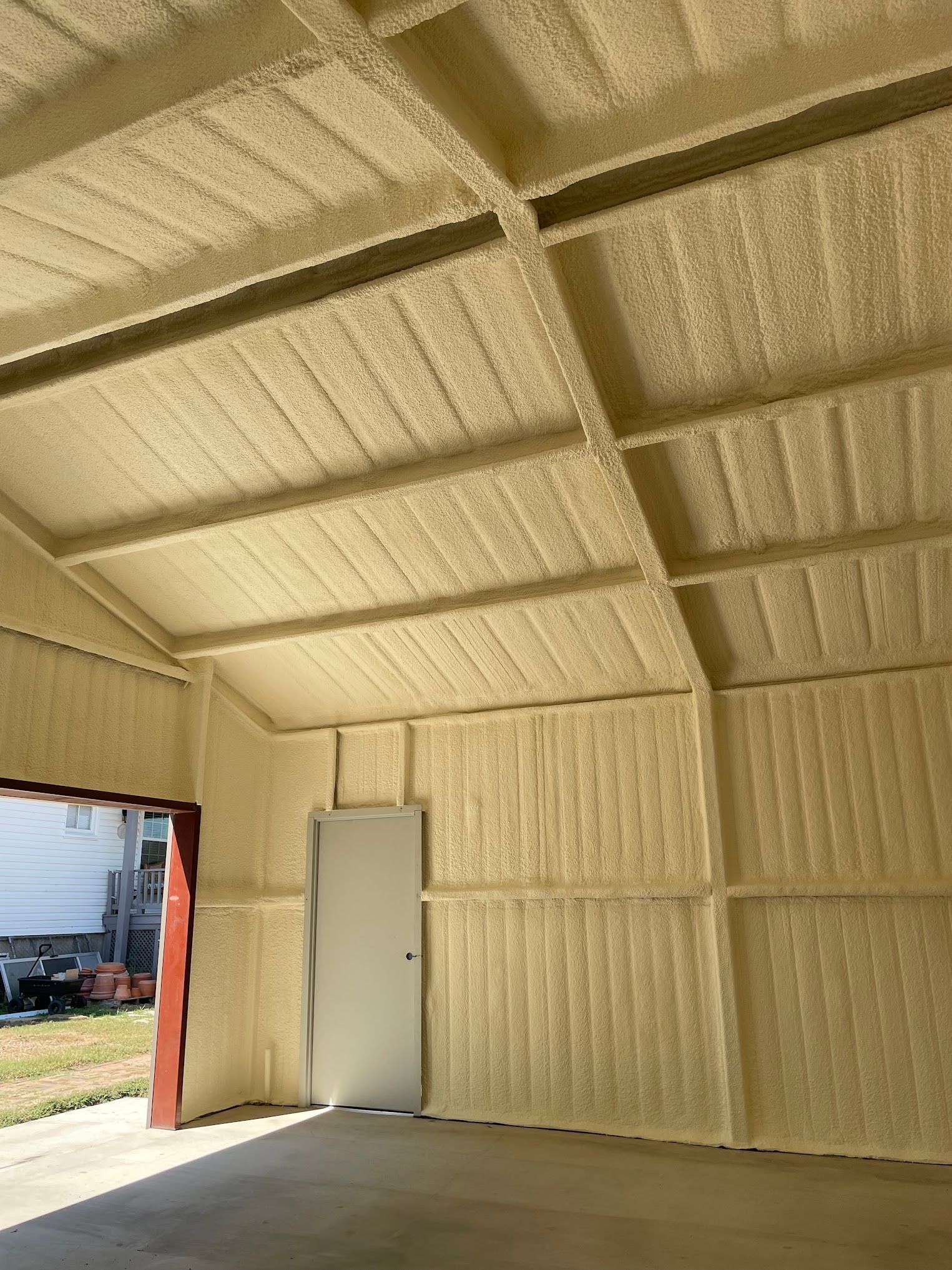 Interior of a building with light yellow spray foam insulation on the walls and ceiling. 