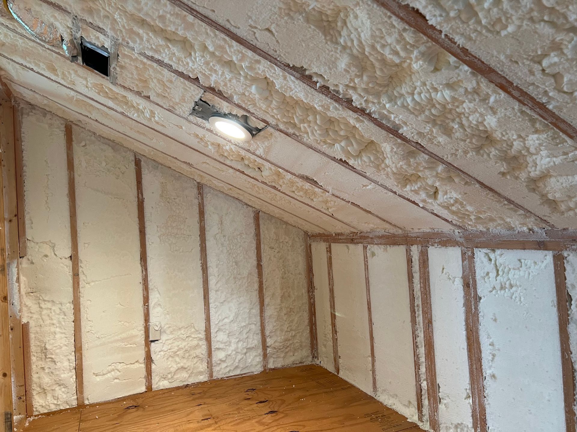 Interior view of an attic with spray foam insulation on the walls and ceiling.
