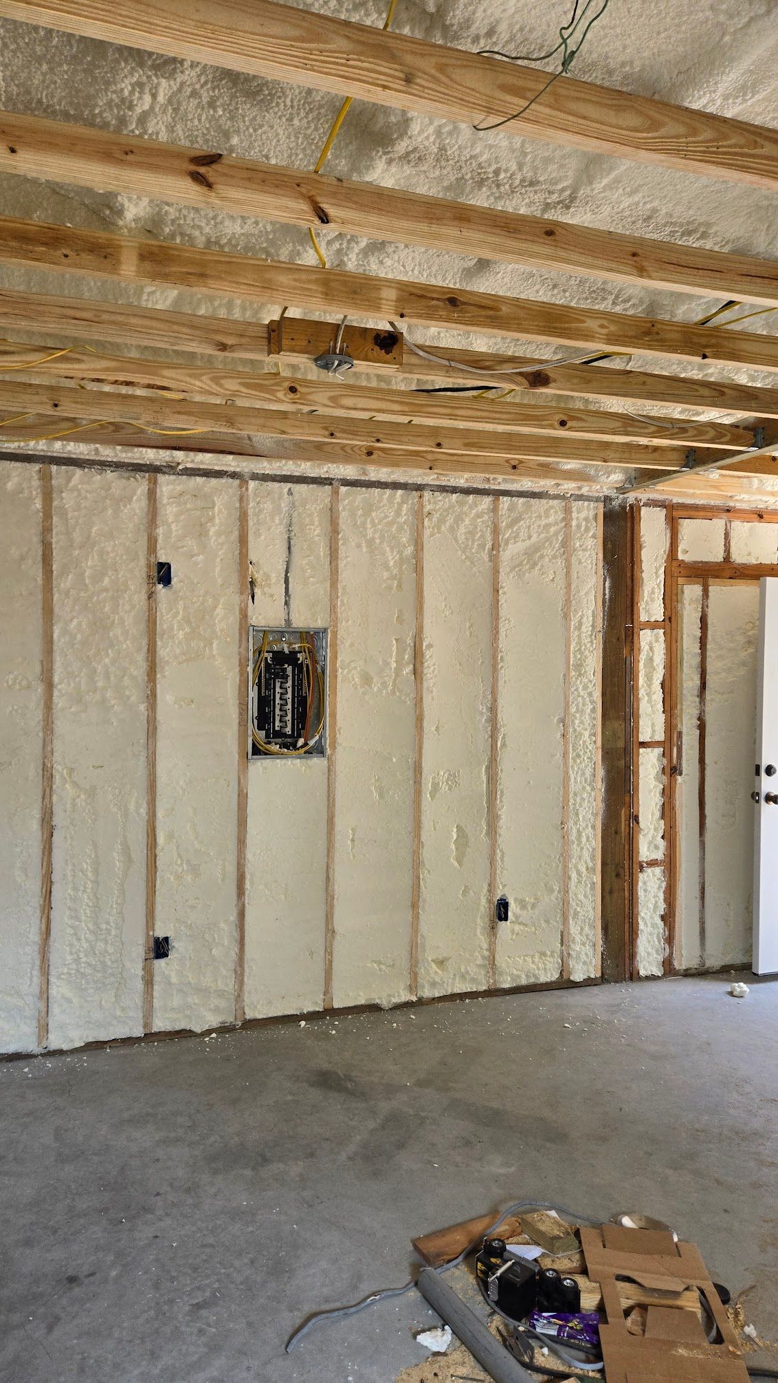 Interior view of a room under construction with spray foam insulation on walls and ceiling.