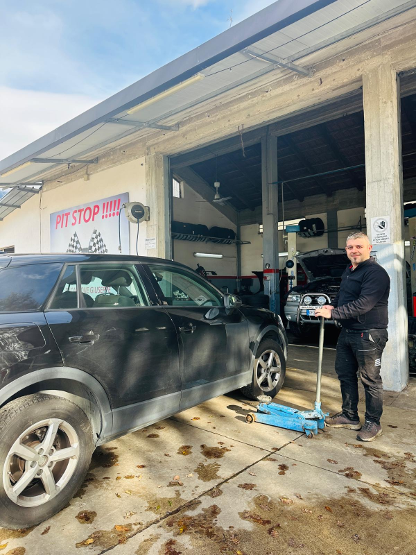 Un uomo è in piedi accanto a un'auto nera in un garage.