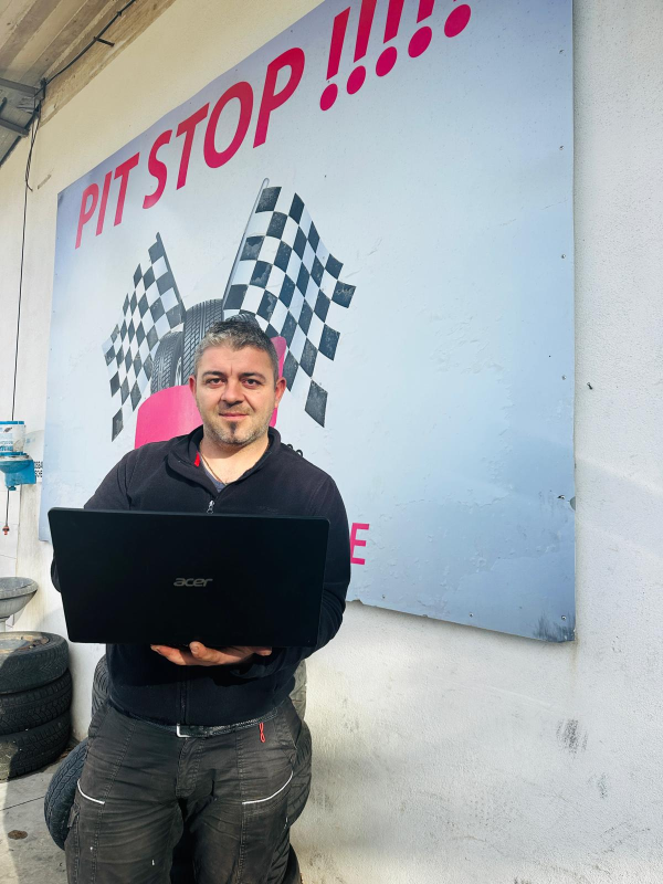 Un uomo che tiene in mano un computer portatile davanti a un cartello che dice pit stop