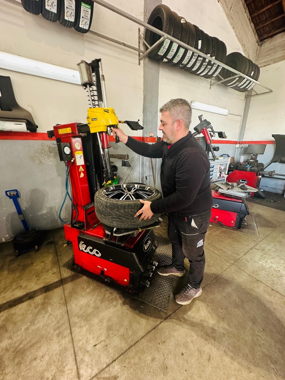Un uomo sta cambiando una gomma su un macchinario in un garage.
