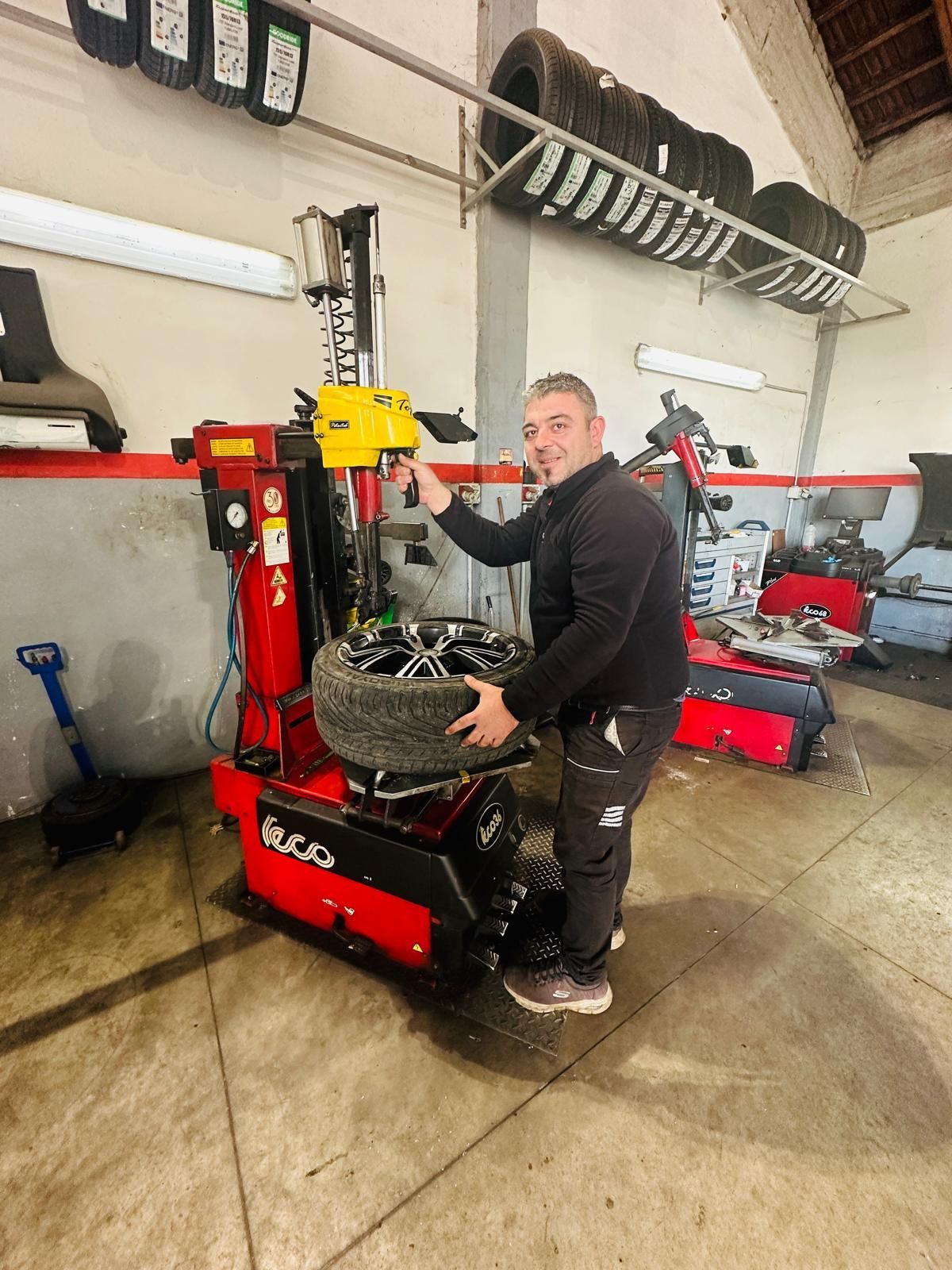 Un uomo sta lavorando su una macchina per pneumatici in un garage.