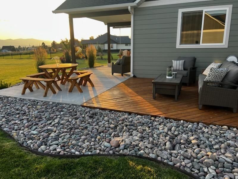 A wooden deck with chairs , a table and a vase of flowers.