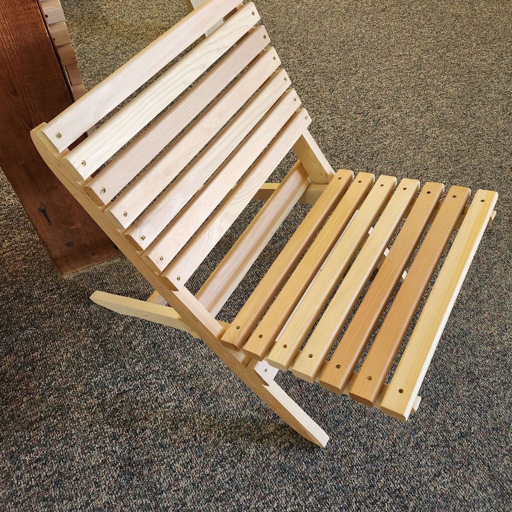 A wooden folding chair is sitting on a carpeted floor,