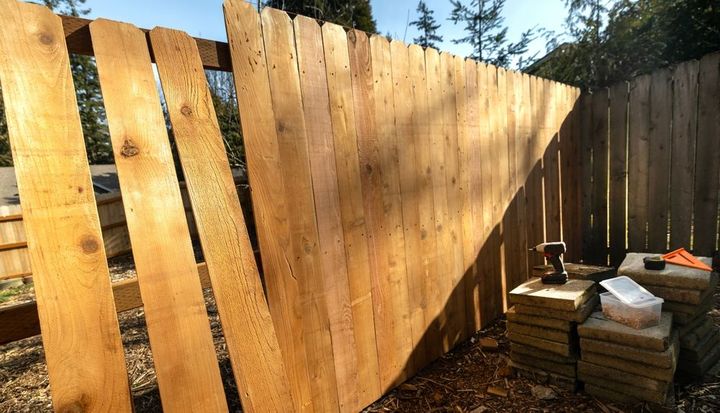 A wooden fence is being built in a backyard.