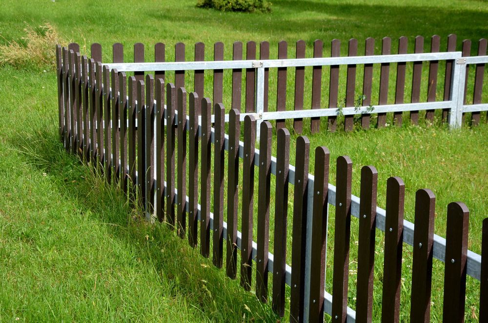 A wooden fence surrounds a lush green field.