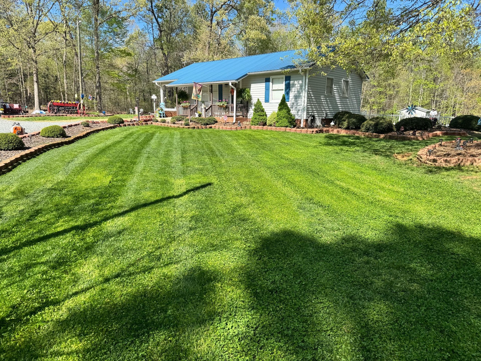 A white house with a blue roof surrounded by a well-manicured lawn. Trees are in the background.
