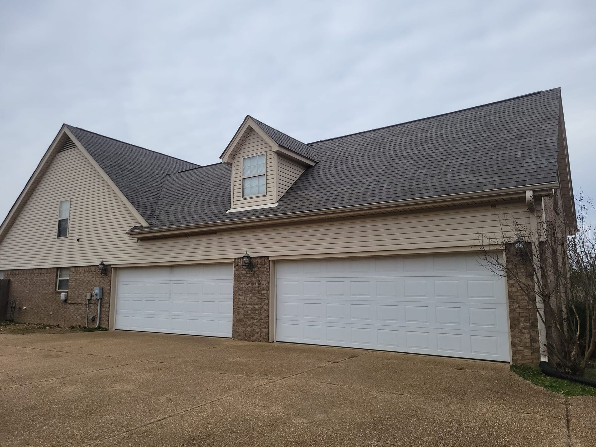 A large house with three garage doors and a gray roof.