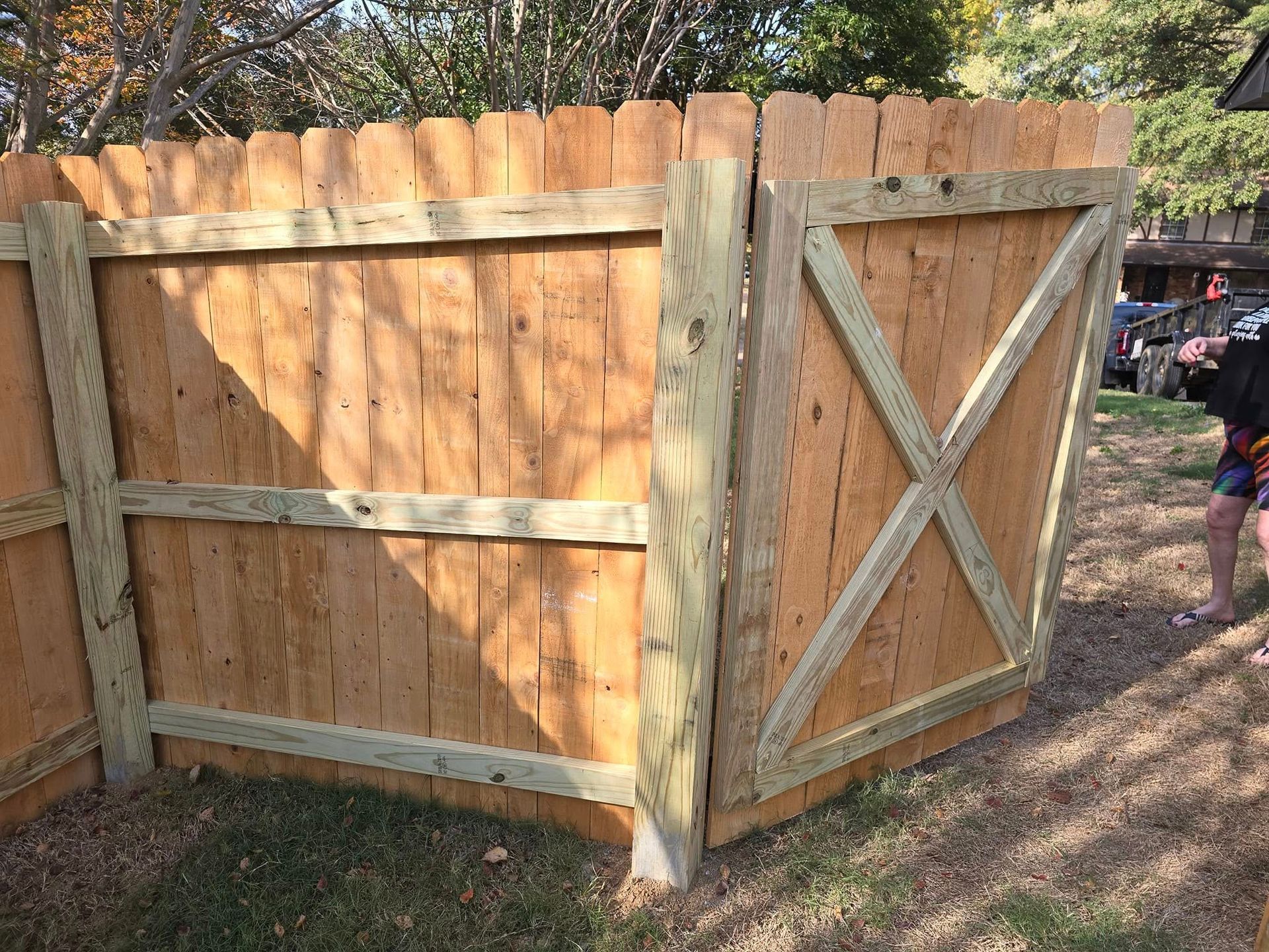 A wooden fence with a wooden gate in the backyard.