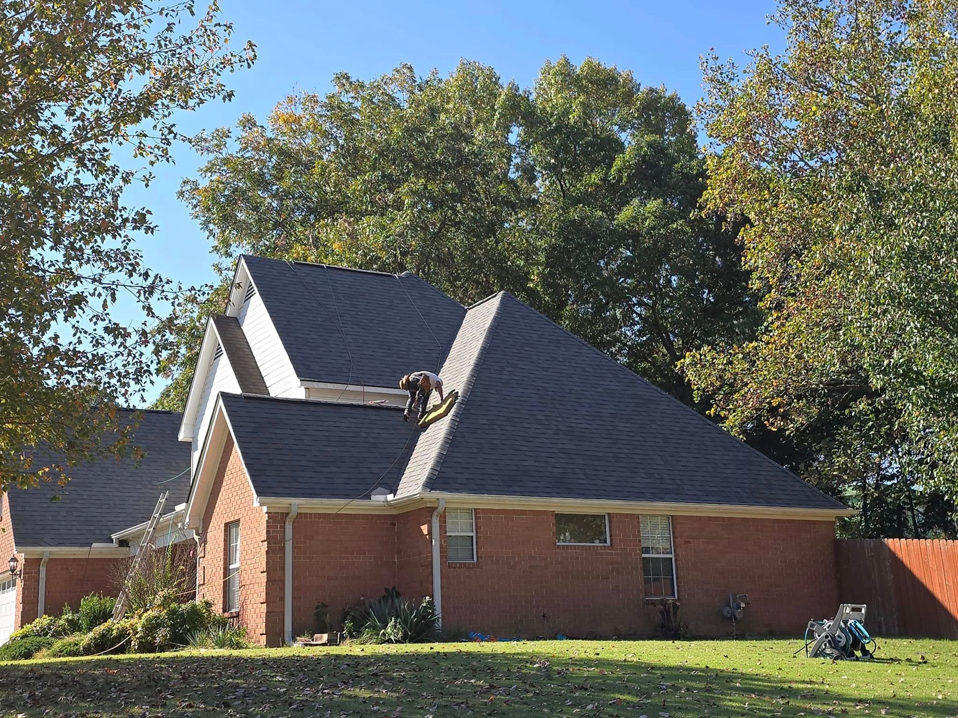 A brick house with a gray roof and trees in the background