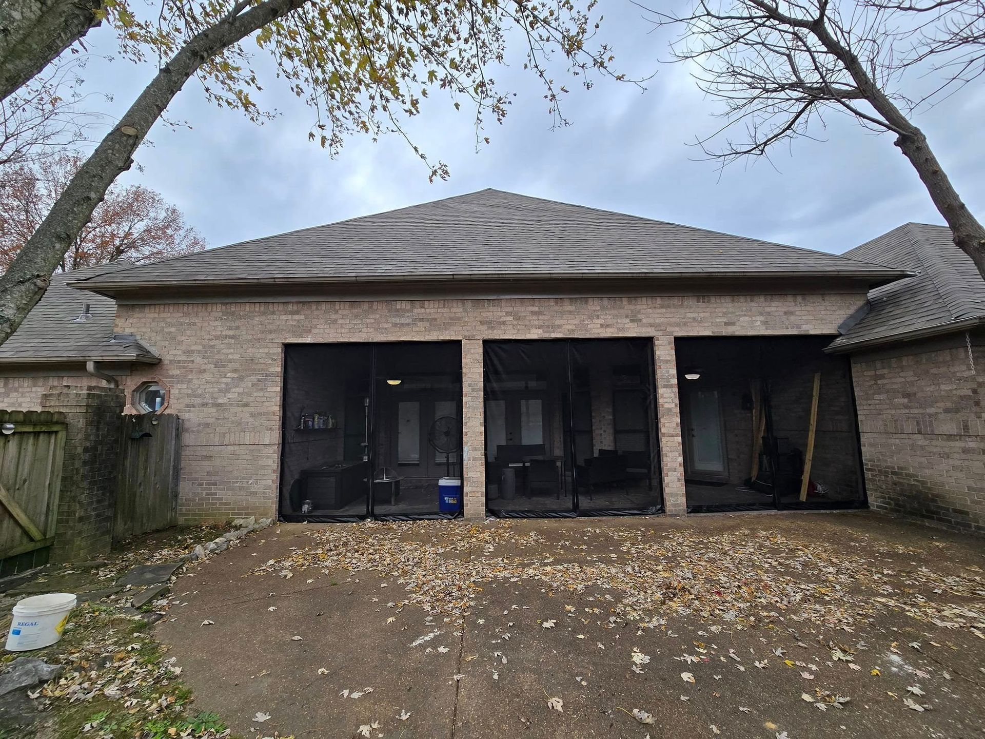 A brick house with three garage doors and a screened in porch.