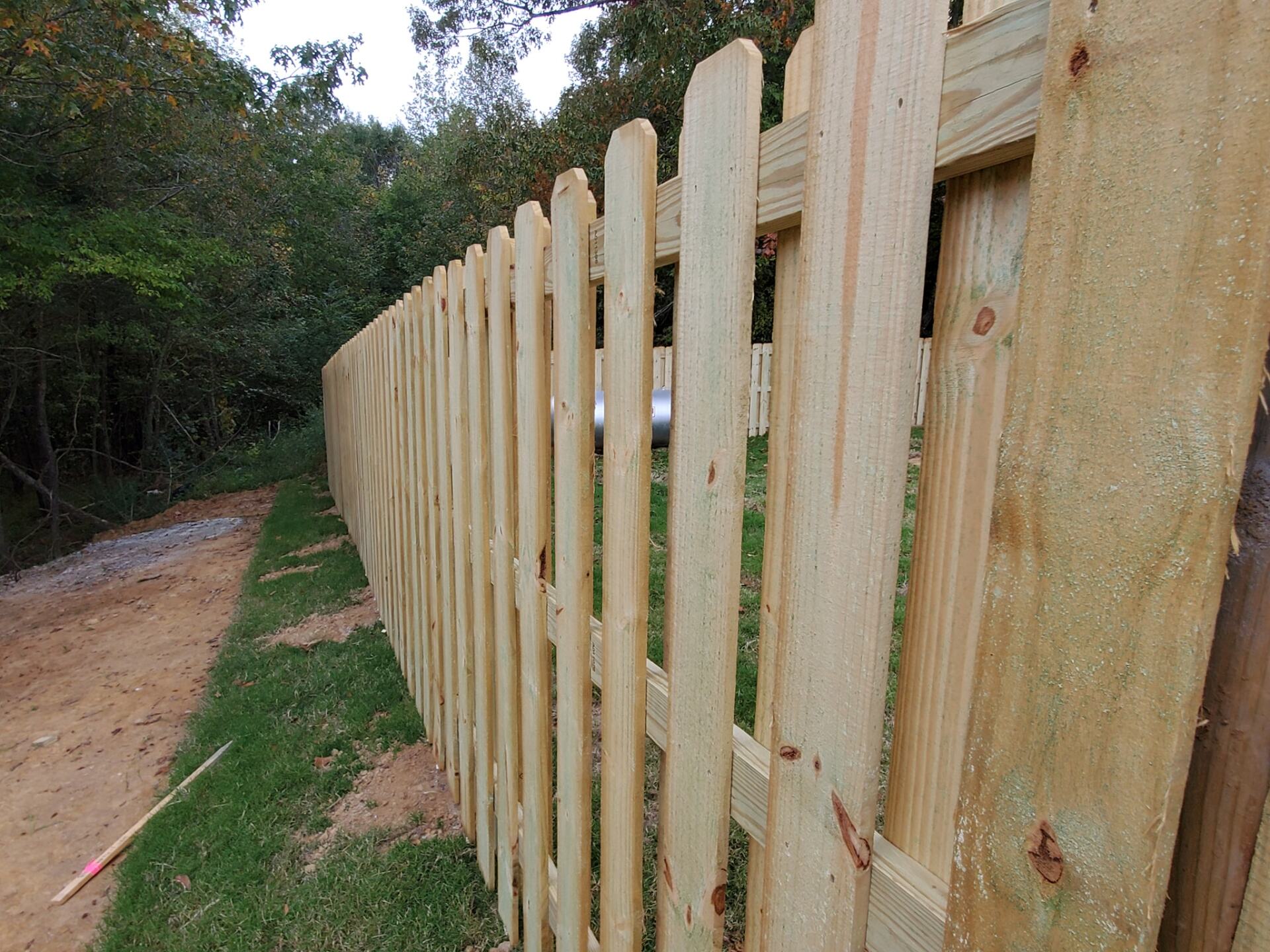 A wooden picket fence along a dirt road
