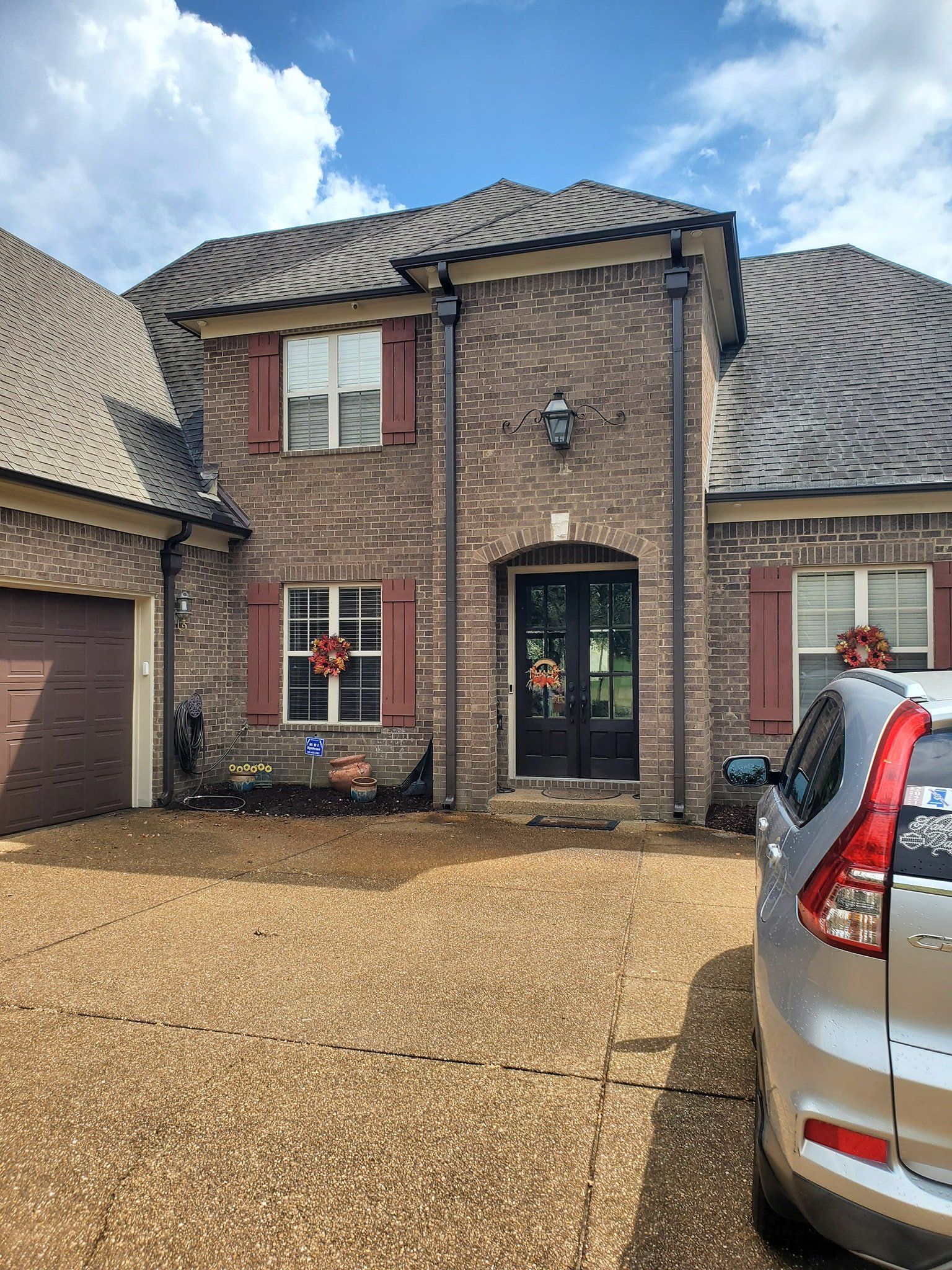 A car is parked in front of a large brick house.