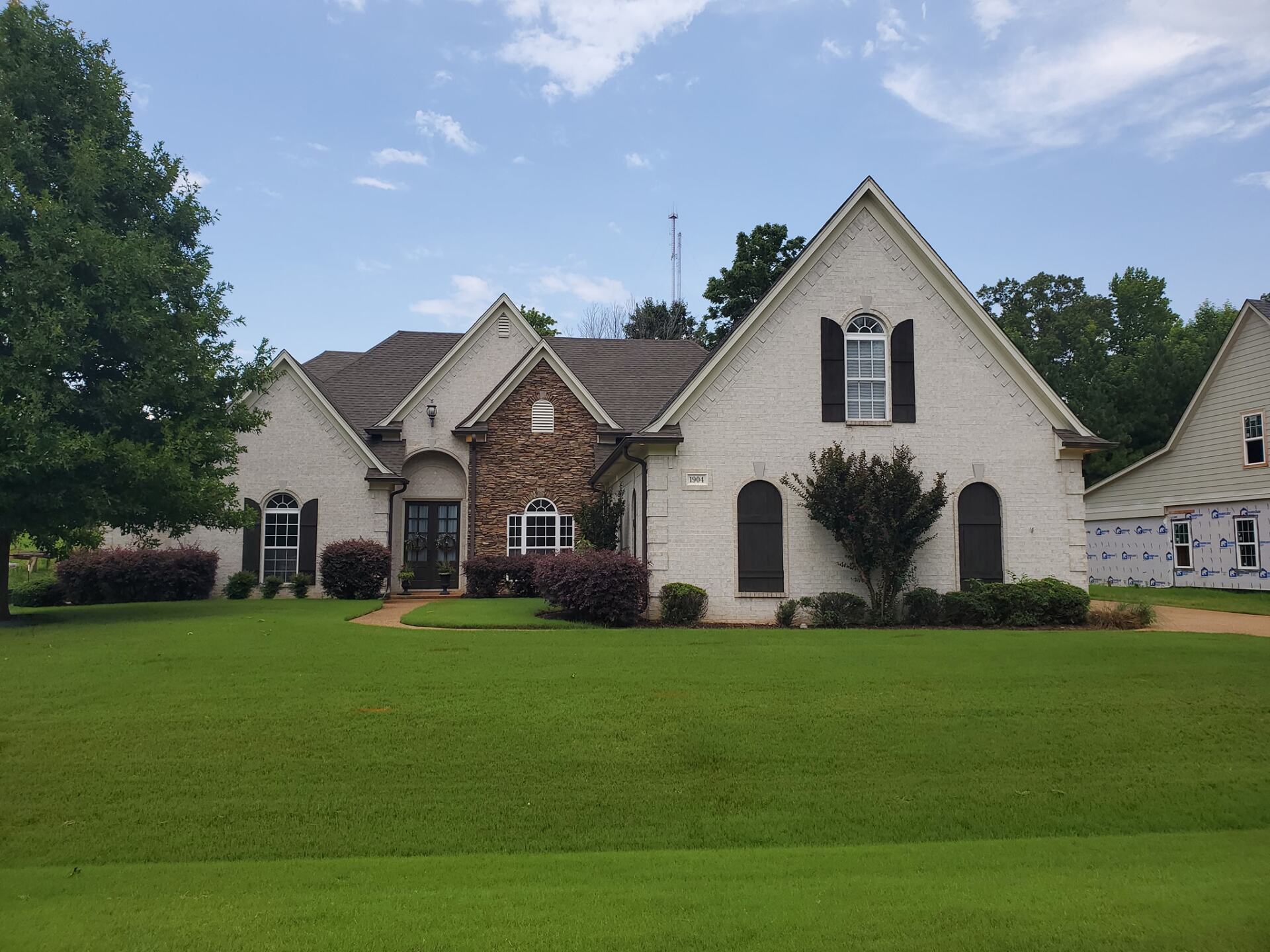 A large white brick house with black shutters on the windows