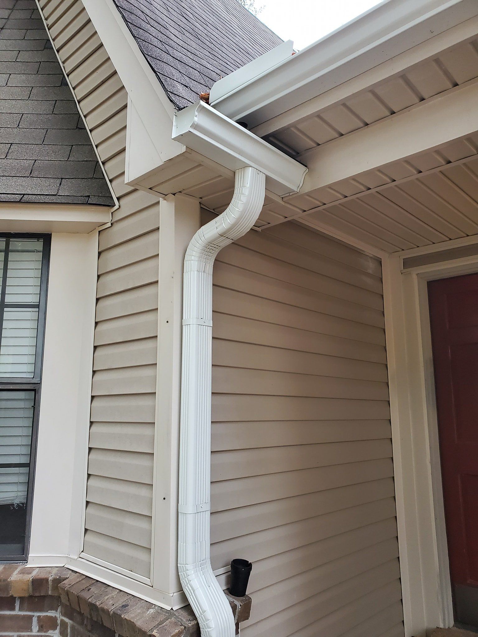 A white gutter is on the side of a house.