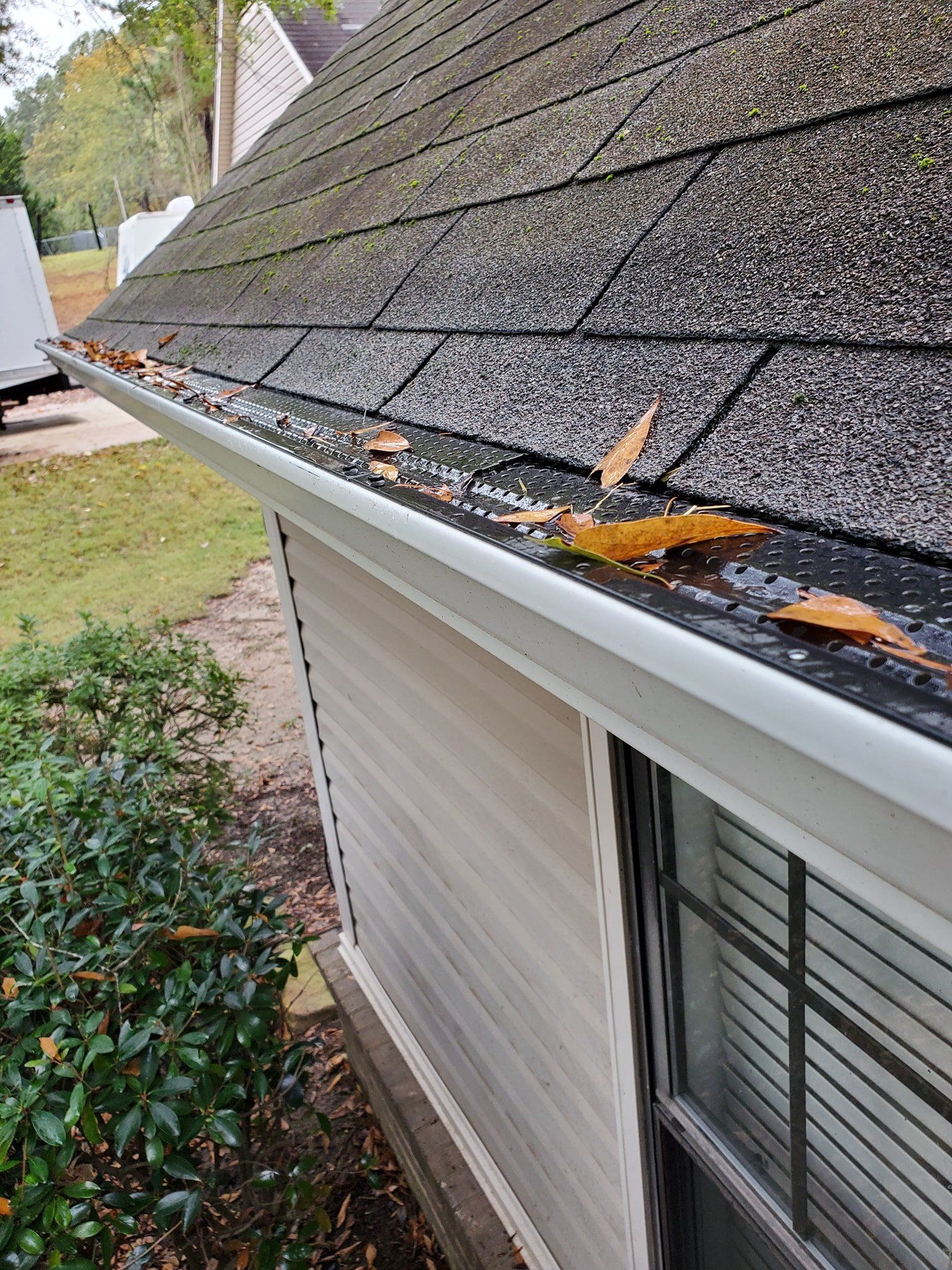 A gutter on the side of a house with leaves on it.