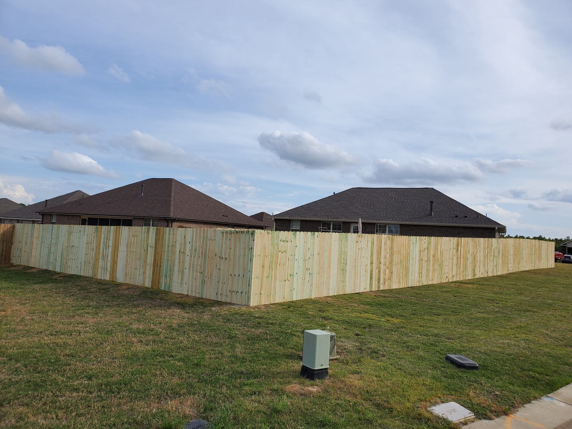 A wooden fence is surrounding a house in a residential area.