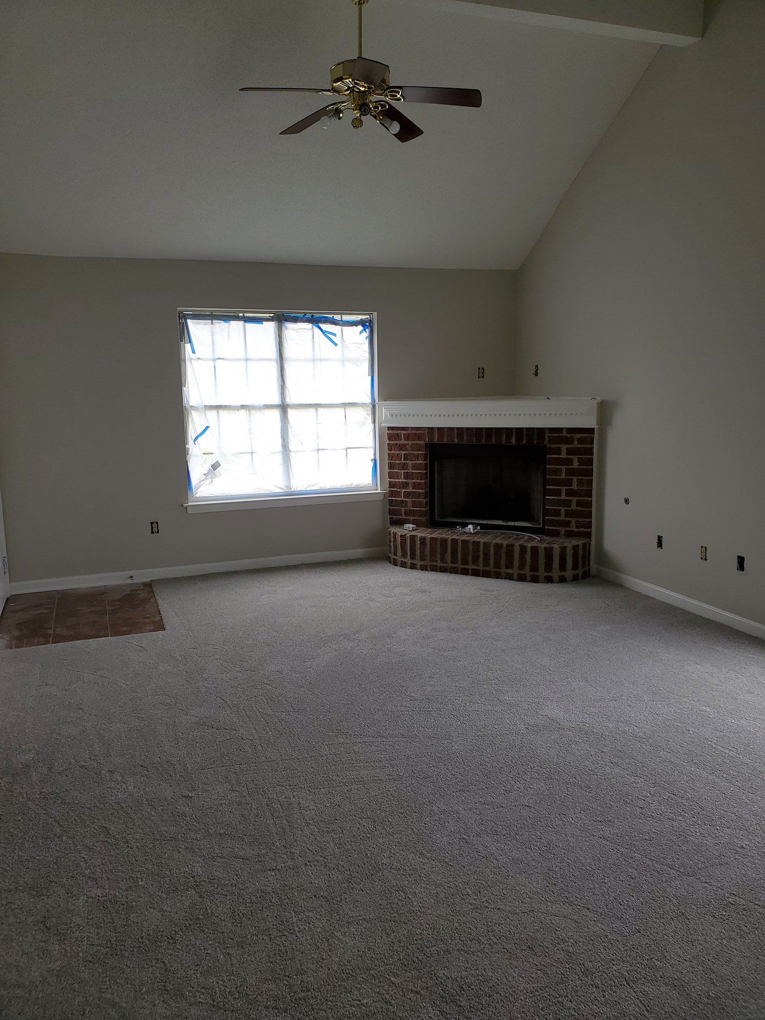 An empty living room with a fireplace and a ceiling fan.