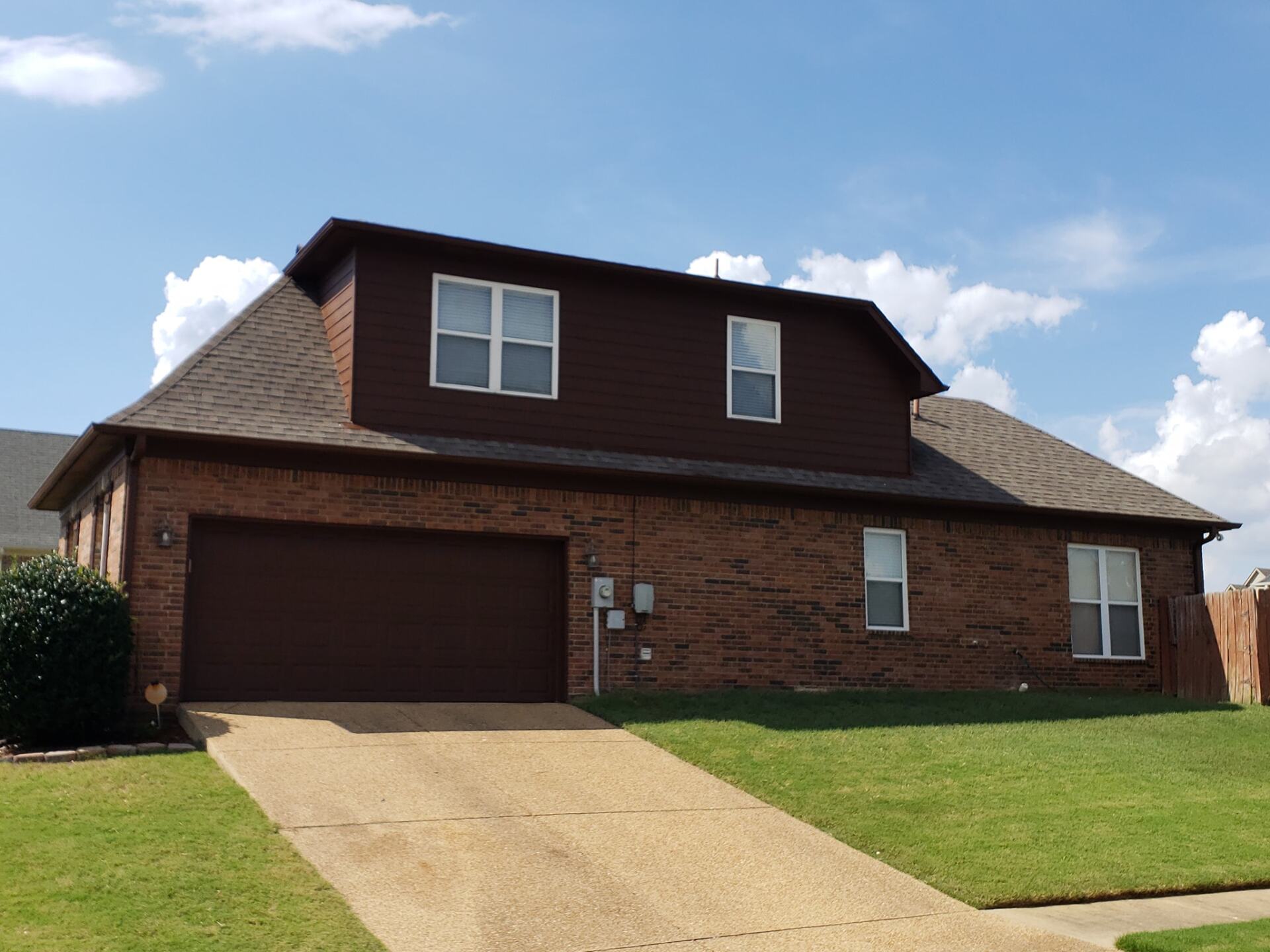 A brick house with a brown garage door
