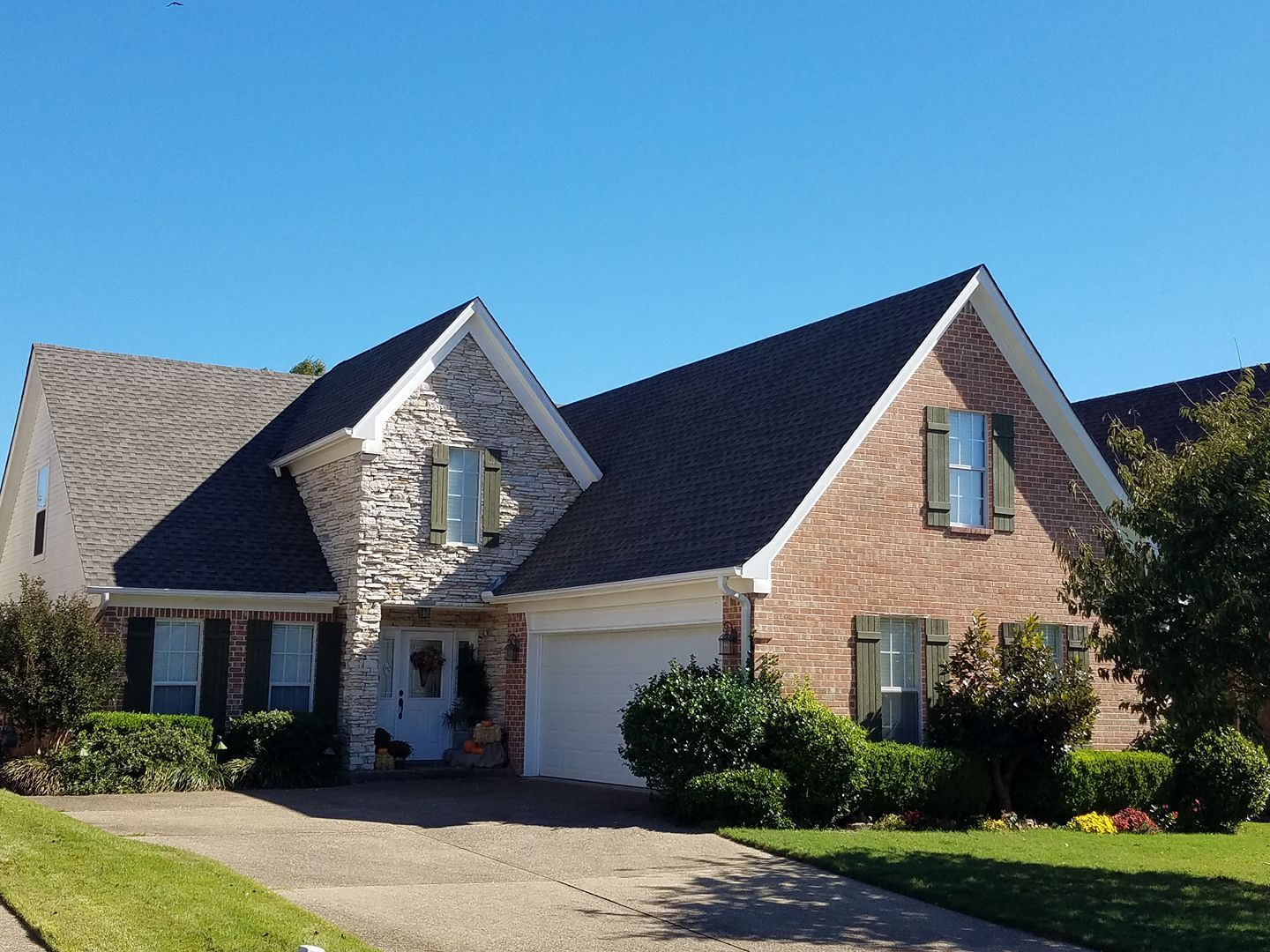 A brick house with a black roof and white shutters