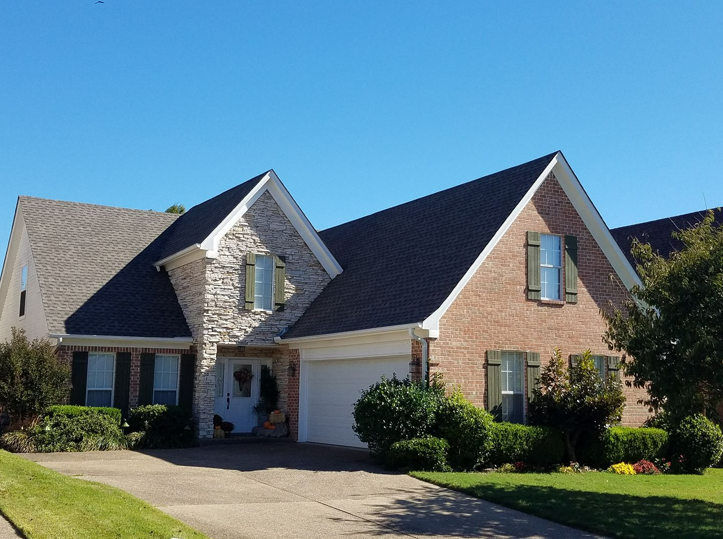 A brick house with a black roof and green shutters